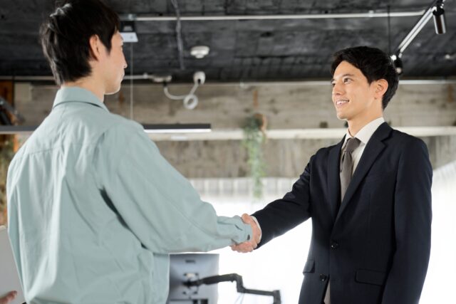 工事業者と握手をするサラリーマン