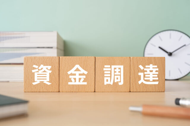 資金調達と書かれたブロックが置かれたデスク