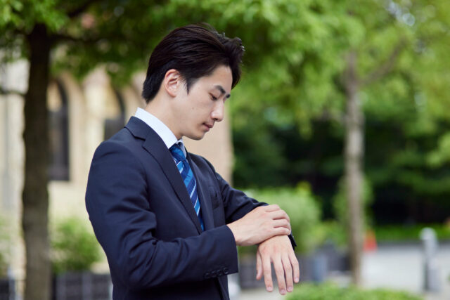 腕時計を見るスーツを着た男性