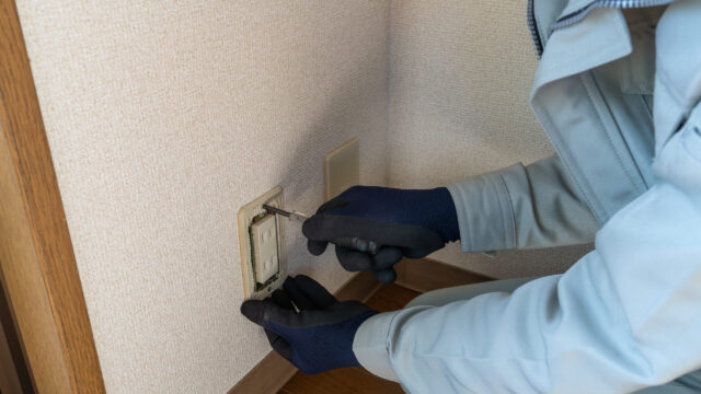 コンセントプレートを修理する作業員。電気工事イメージ